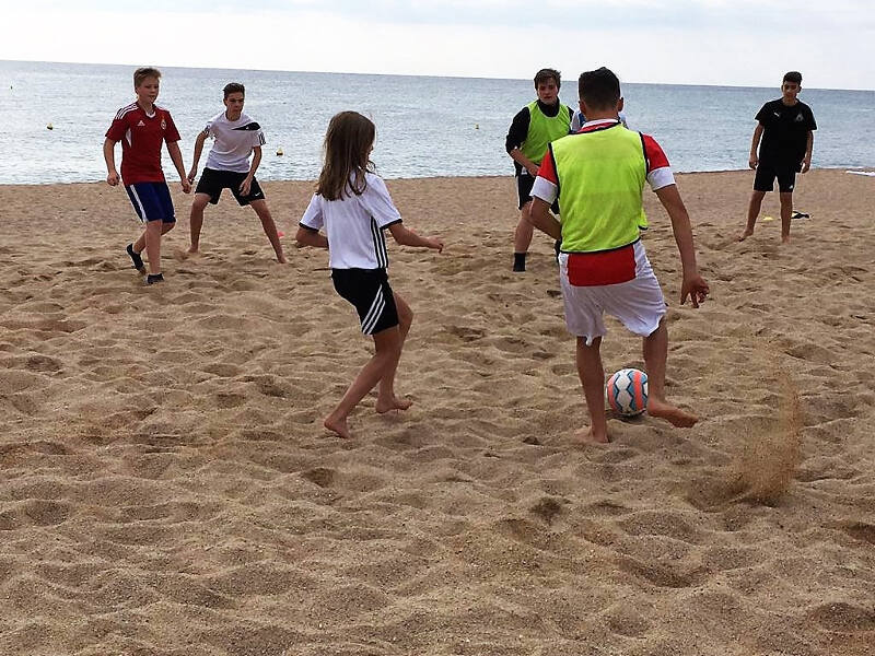 Jungs spielen Fußball am Strand im Feriencamp Barcelona