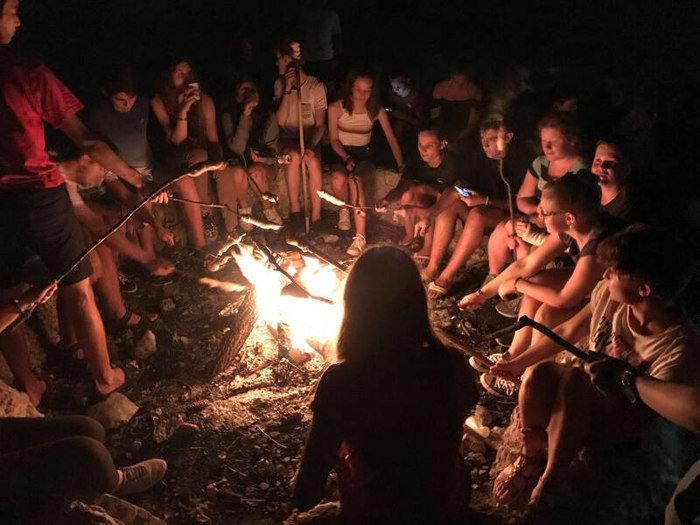 Teilnehmer eines Ferien-Sprachkurses sitzen am Lagerfeuer
