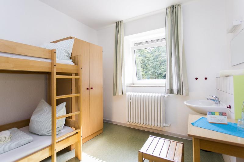Die Unterkunft im Fußballcamp ist ein heller Raum mit einem Stockbett, Waschbecken und Tisch