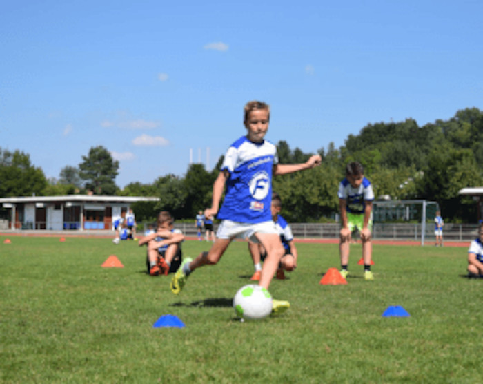 Im Fußballcamp schießt ein Junge den Ball Richtung Tor