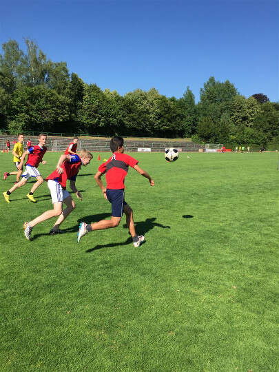 Jungs laufen über Rasenplatz im Fußballcamp Köln