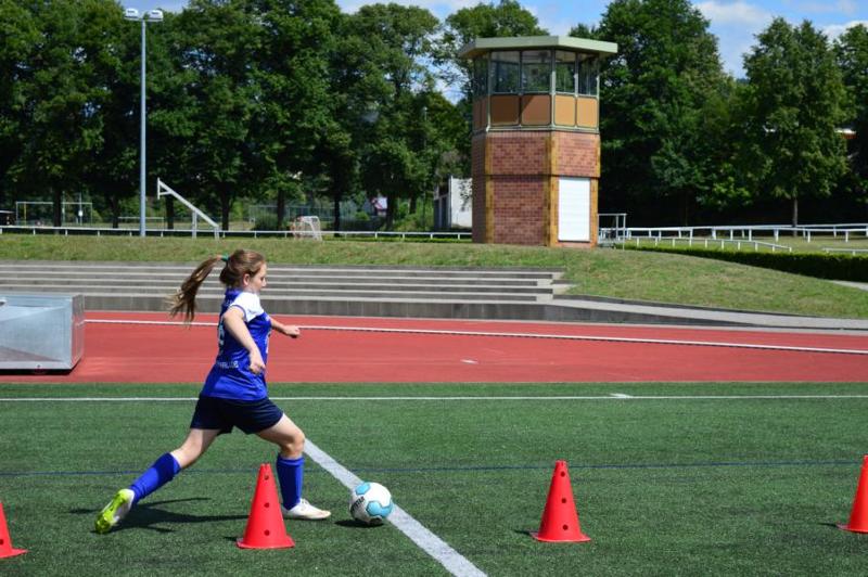 Ein Mädchen im Ferienprogramm Rheinland-Pfalz hat Spaß beim dribbeln um die Fußballhütchen