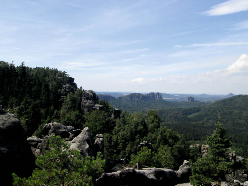 Grüne Hügel und schroffe Felsen erstrecken sich unter blauem Himmel im Feriencamp Sachsen