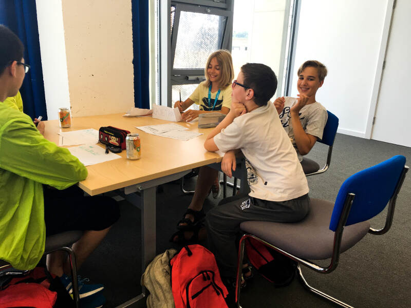 Jugendliche sitzen beim Englischunterricht in einem Seminarraum beisammen