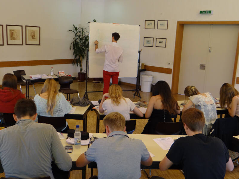 Die Schüler aus dem Ostercamp sitzen an ihren Plätzen und schreiben mit, während der Lehrer an der Tafel etwas erklärt