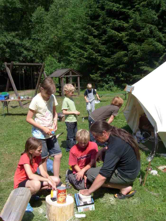 Kinder und Betreuer kochen zusammen auf dem Zeltplatz im Ferienlager in Thüringen