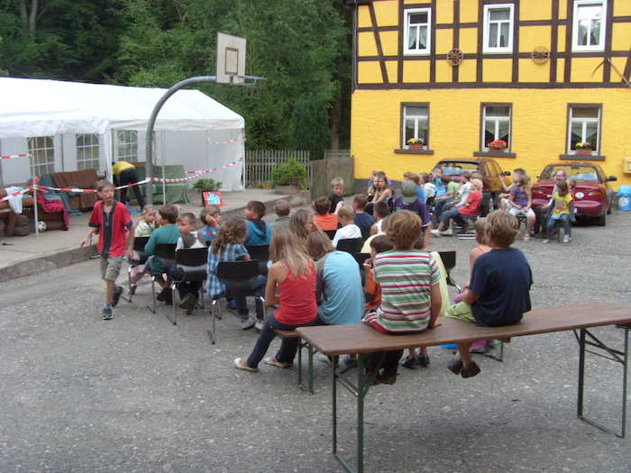 Kinder sitzen draußen zusammen im Ferienlager in Thüringen