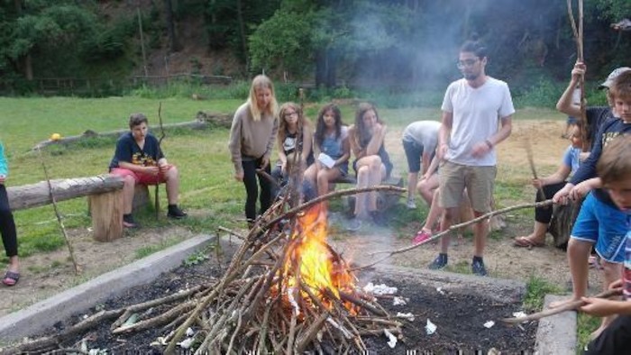 Kinder sitzen ums Lagerfeuer herum im Ferienlager in Thüringen