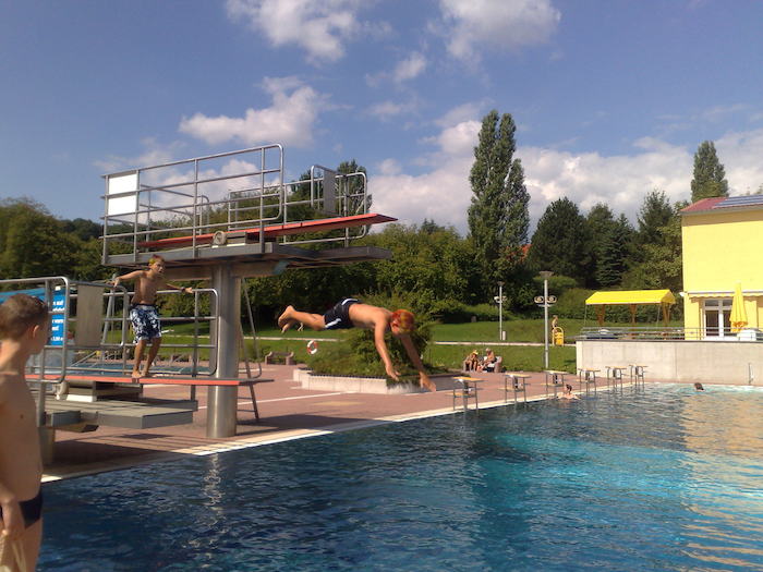 Junge springt vom Brett in den Pool im Ferienlager in Thüringen