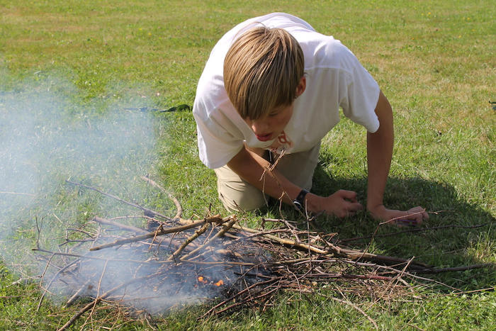 Junge macht ein Feuer im Herbstcamp Johanngeorgenstadt