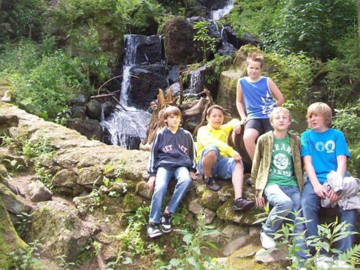 Kindergruppe sitzt vor einem Wasserfall im Herbstcamp Johanngeorgenstadt