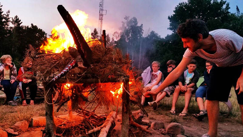 Gruppe sitzt am Lagerfeuer im Englisch Adventurecamp