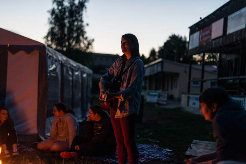 Mädchen spielt Gitarre am Lagerfeuer im Englischcamp