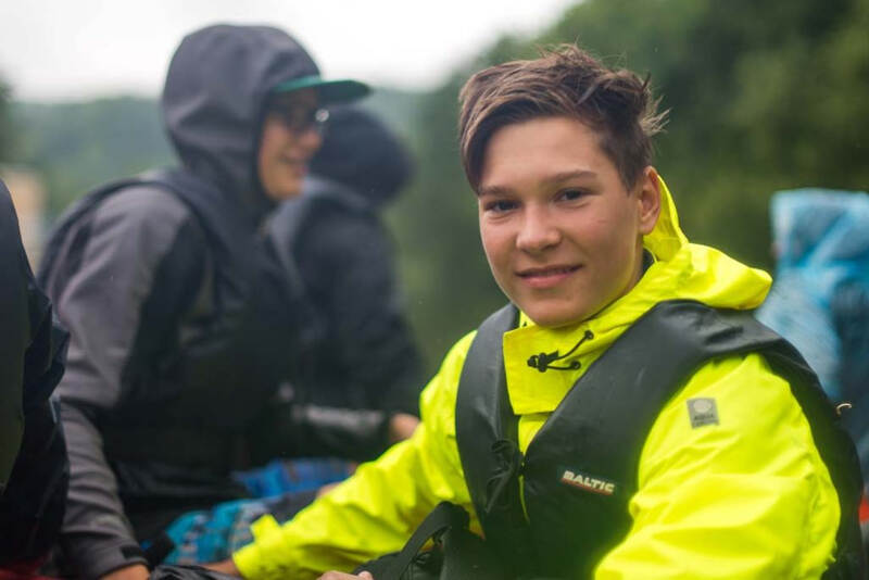 Junge in wasserfester Kleidung während Kanutour im Sommercamp