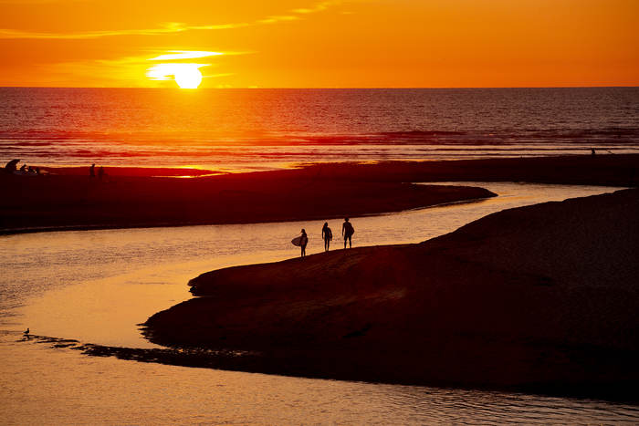 Jugendliche stehen im Surf-Camp Südfrankreich beim Wasser, betrachten den malerisch schönen Sonnenuntergang