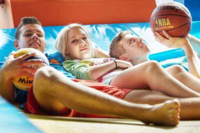Jugendliche liegen entspannt auf einem Trampolin in der Sporthalle des Jugendhotels Club Kitzsteinhorn in Zell am See