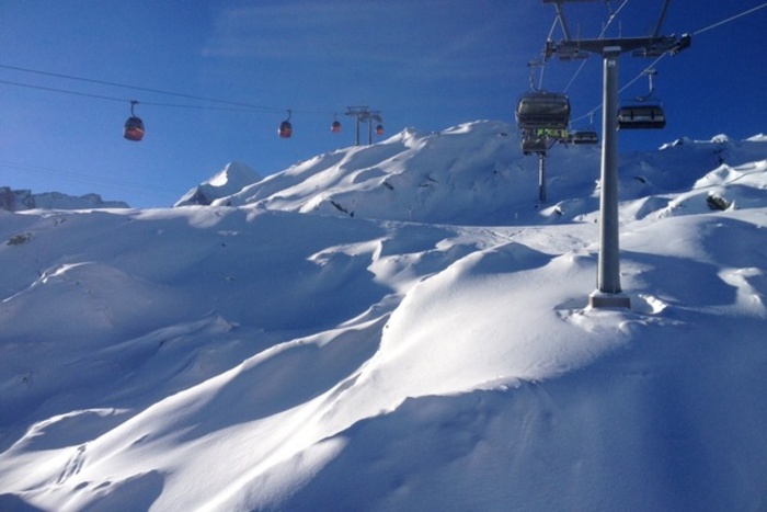 Seilbahngondeln fahren bei Sonnenschein einen schneebedeckten Berghang im Salzburger Alpenland hinauf und hinunter