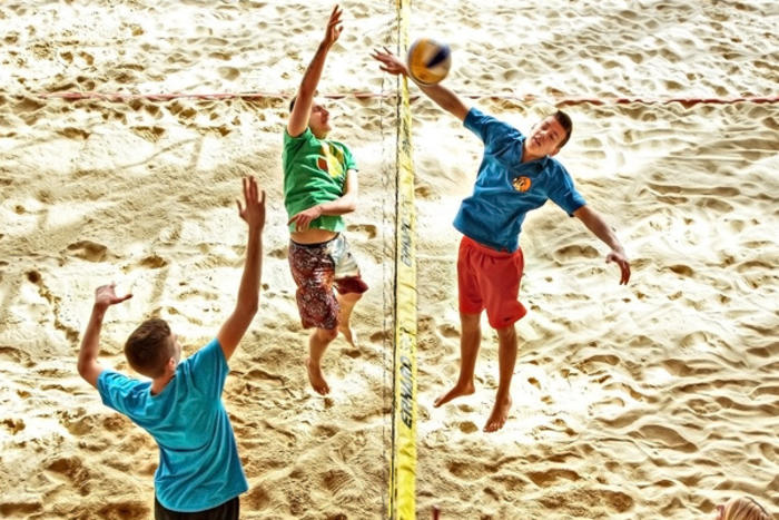 Jugendliche beim Angreifen und Blocken am Netz auf einem Beachvolleyballfeld im Jugendhotel Club Kitzsteinhorn in Zell am See