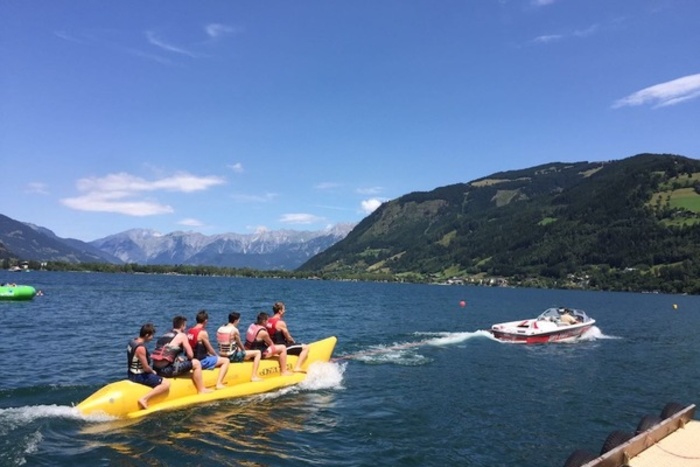Junge Feriengäste werden auf einer Wassersport-Banane über den sommerlichen Zeller See gezogen