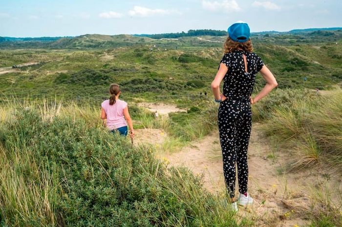 Meisjes kijken uit over de duinen. 