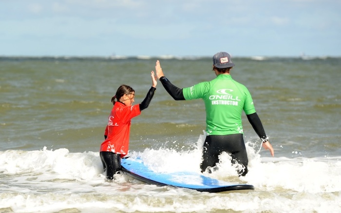 Meisje geeft trainer high-five in het water. 