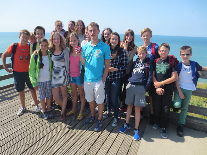 Groep jongeren poseert aan zee. 