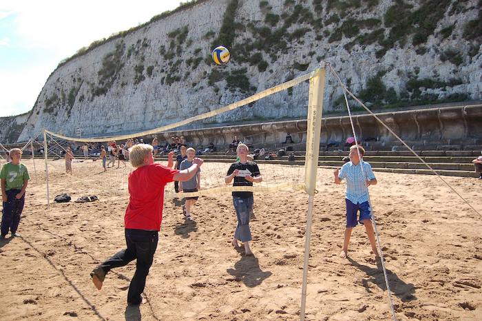 Kinderen op Engels taalkamp spelen beachvolleybal.