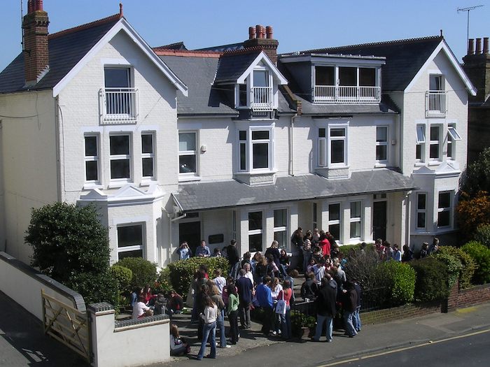 Deelnemers taalkamp Engels staan bij mooi witte huis, accommodatie in Engeland.