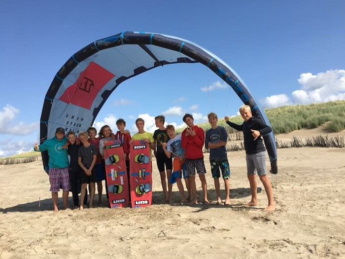 Die Jugendlichen vom Ferienlager 14 Tage posieren mit den Kitesurf-Utensilien auf einem Gruppenfoto