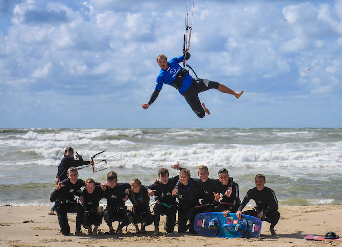 Bei einem Gruppenfoto einer Ferienfreizeit Köln hängt ein Teamer an einem Kite über der Gruppe