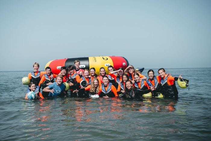 Eine Gruppe einer Ferienfreizeit Holland kniet im Meer