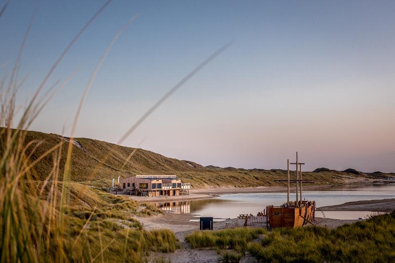 Auf dem Bild der Sprachreisen 2 Wochen sieht man eine Landschaft mit Hügeln und Gewässer, ein Haus und ein Boot