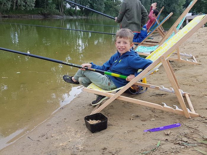 Jongetje met hengel poseert voor de camera op viskamp.