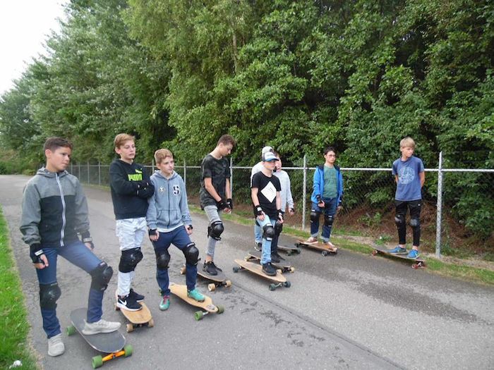 Kinder eines internationalen Feriencamps fahren Longboard