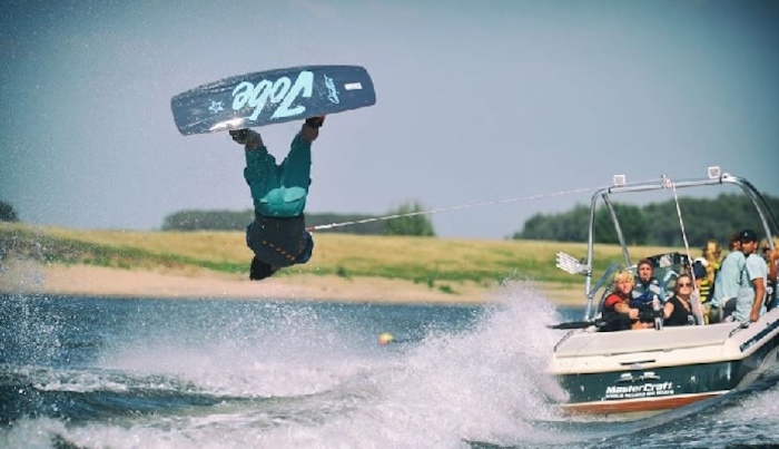 Kinder eines internationalen Feriencamps fahren Wakeboard