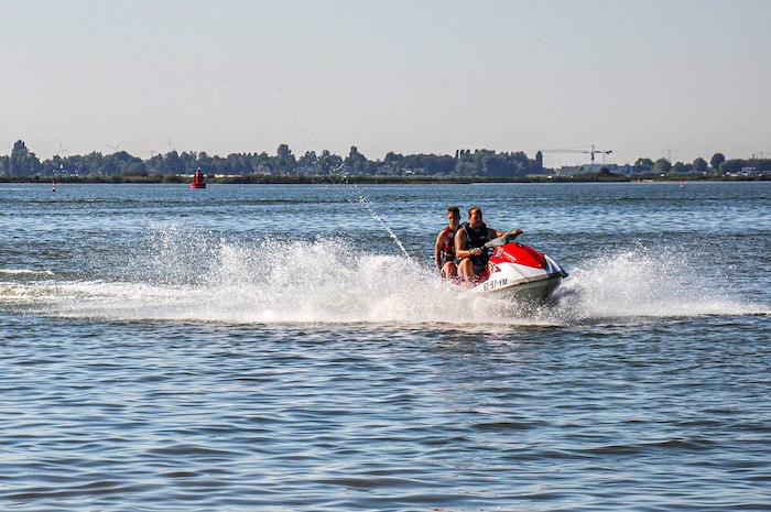 Kinder eines internationalen Feriencamps fahren Motorboot