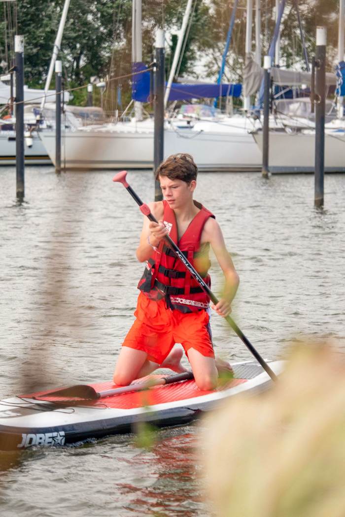 Kinder eines internationalen Feriencamps fahren SUP