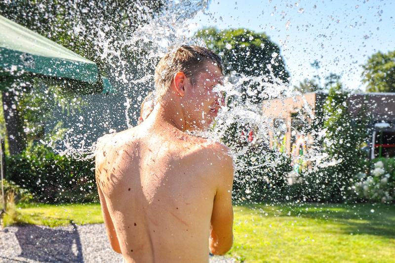 Kinder eines internationalen Feriencamps machen eine Wasserschlacht
