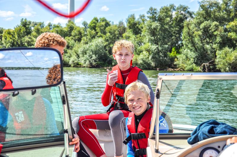Kinder eines internationalen Feriencamps fahren Boot
