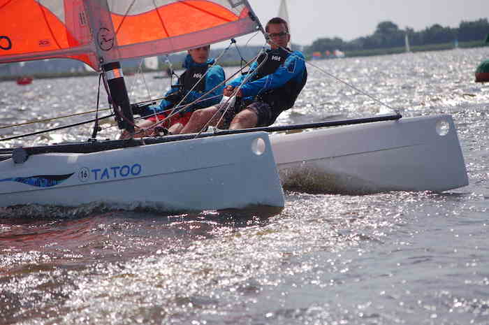 Teilnehmer eines Segelcamps fahren Katamaran