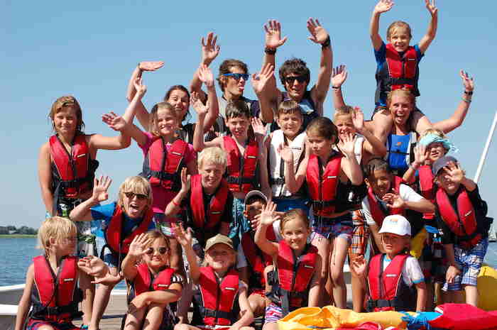 Kinderen in rode reddingsvesten poseren voor de camera. 