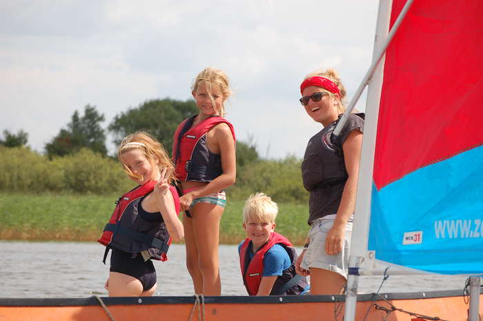 Eine Gruppe Kinder von der Segelfreizeit Nordsee stehen auf einem Boot.