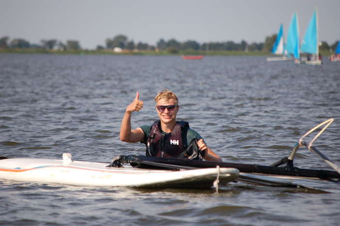 Jongen steekt duim op tijdens windsurfkamp