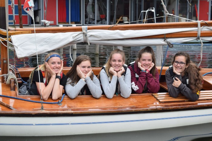 Tienermeisjes poseren lachend op zeilboot.