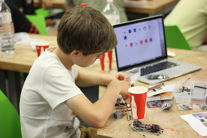 Op kamp Leuven werkt jongen aan robotje. 