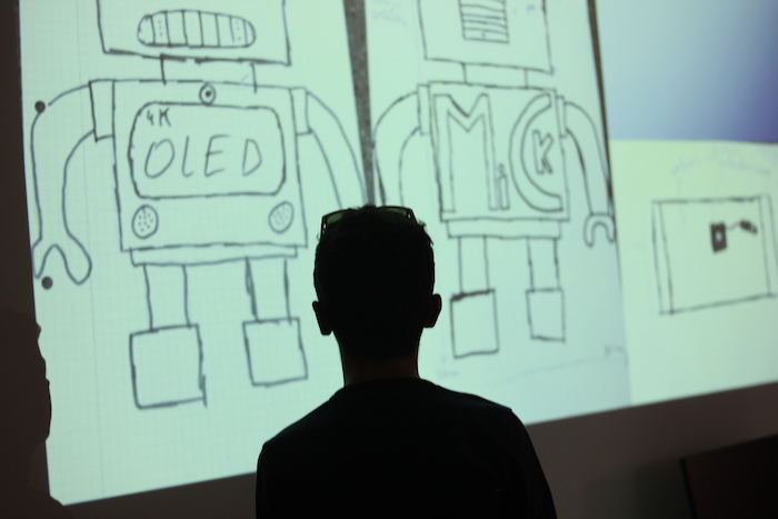 Silhouet van tienerjongen die op kamp naar scherm kijkt met geprojecteerde robots. 
