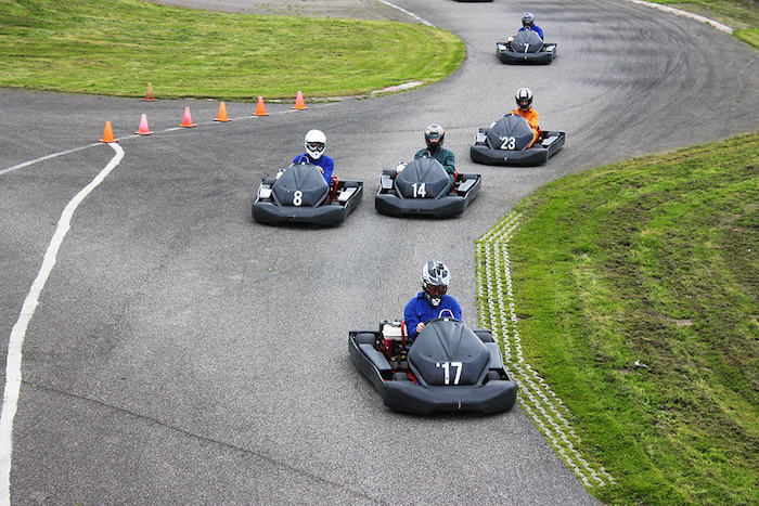 Jongens racen in auto'tjes op grijs asfalt tijdens game kamp. 