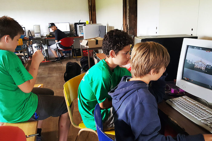 Jongens kijken geconcentreerd naar computerscherm op computerkampkamp.