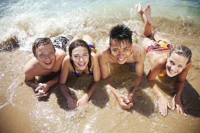 Gruppe liegt am Strand im Wasser und lacht im Ferienlager an der Ostsee