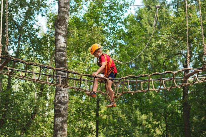 Junge klettert im Hochseilgarten im Feriencamp in den Niederlanden